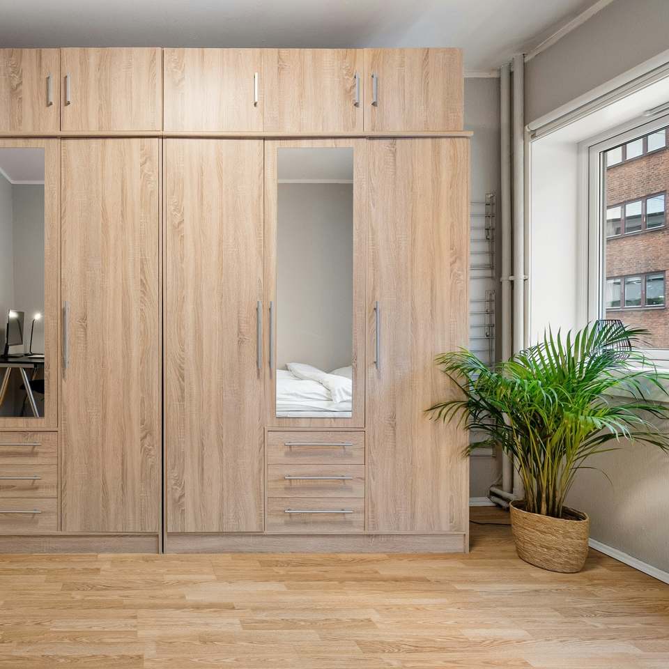 Oak fitted wardrobes with mirrored doors along a bedroom wall